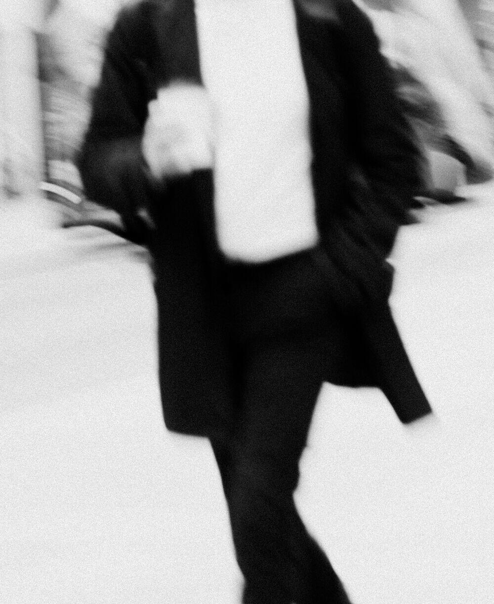 A person mid-stride on a city street, motion-blurred