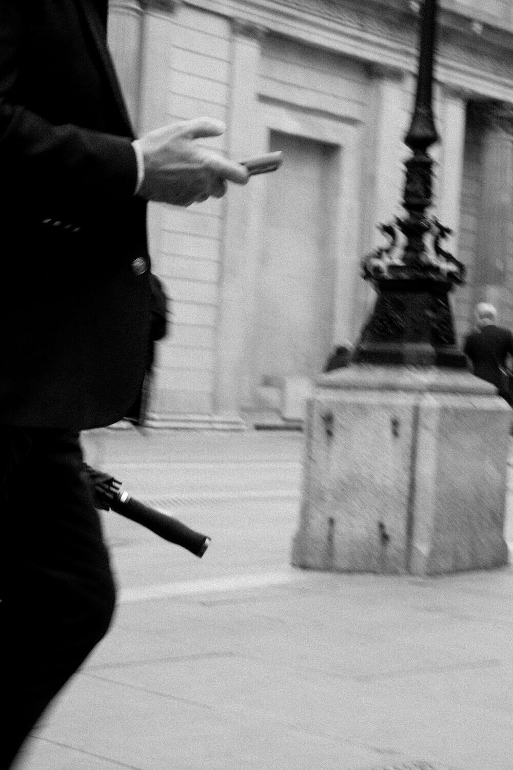 A person checking their phone on a city street, motion-blurred