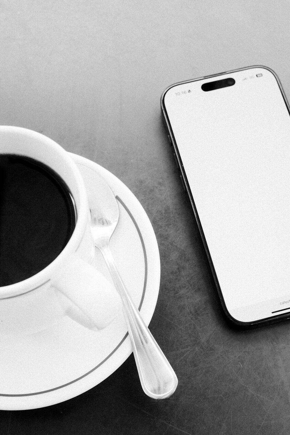 A phone beside an espresso cup