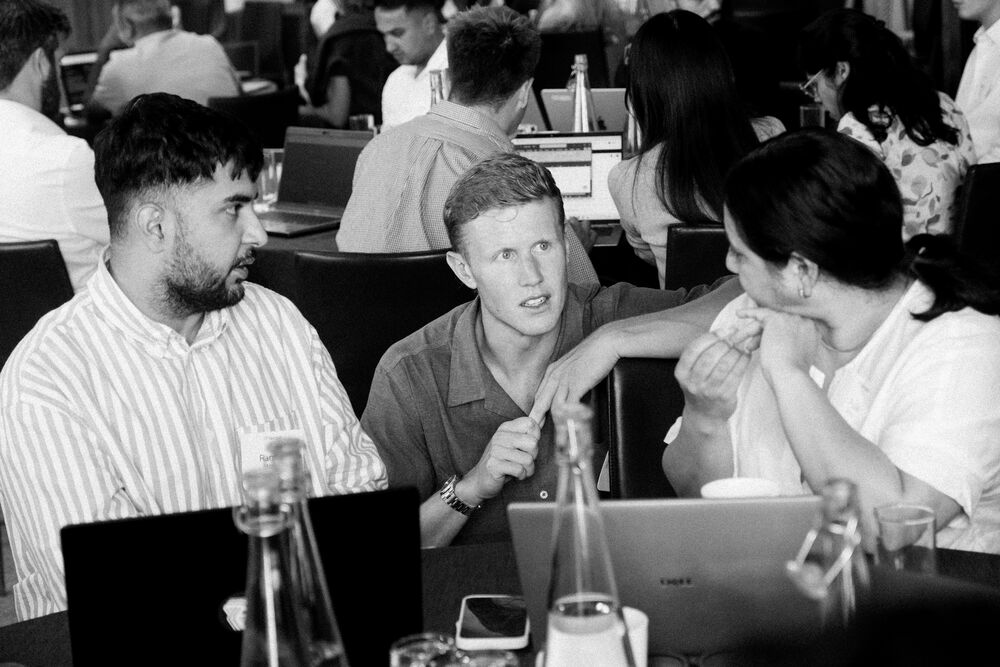 A partner explaining across a table of laptops at a Light event