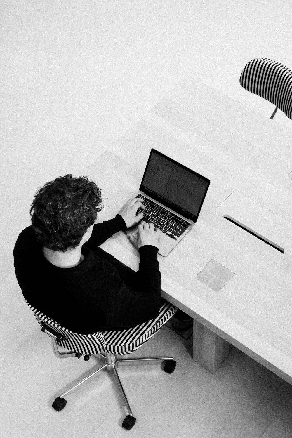 Seen from above, a person reading a report on a laptop at a clean desk