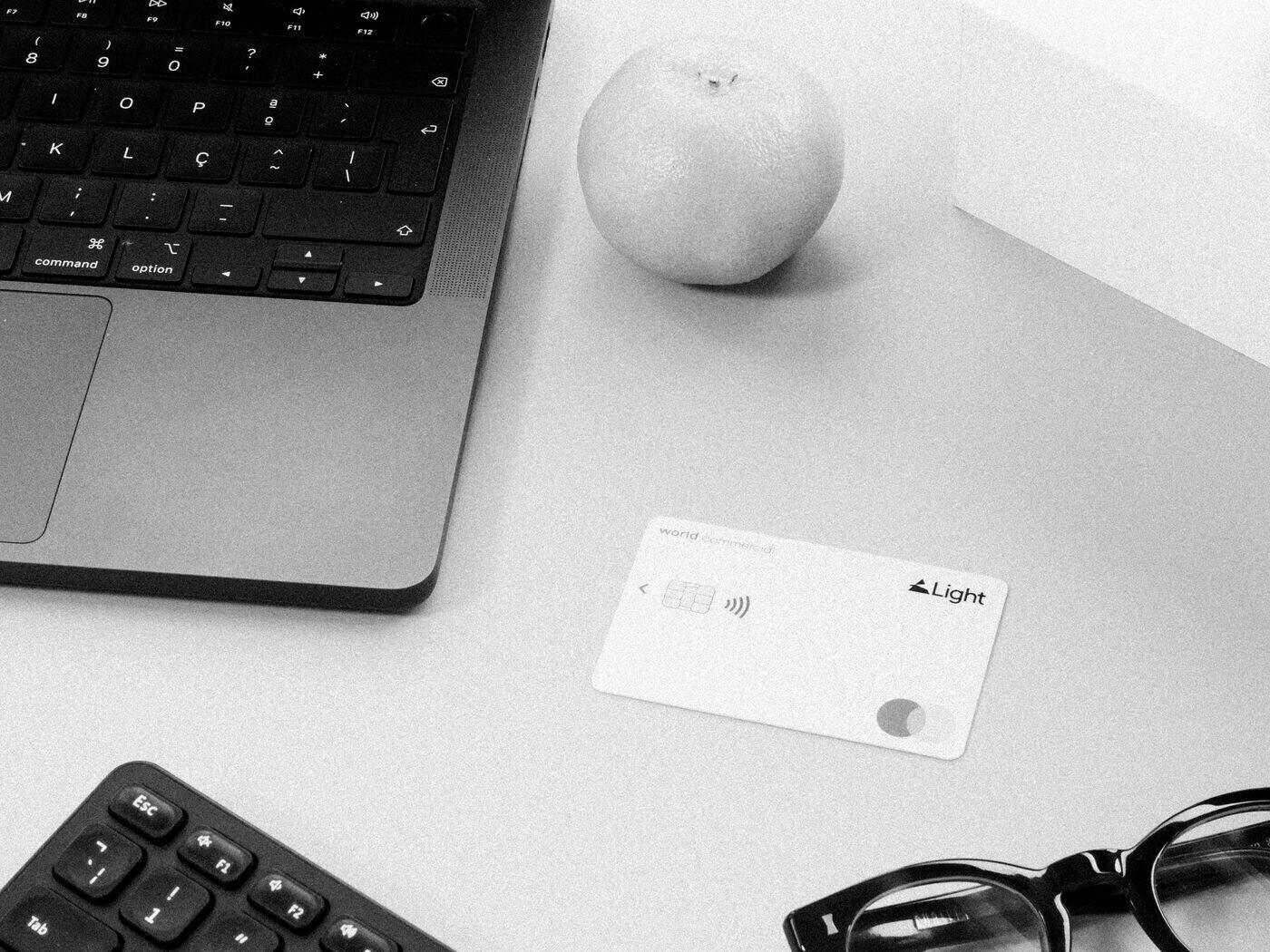 A Light card on a desk beside a laptop and glasses