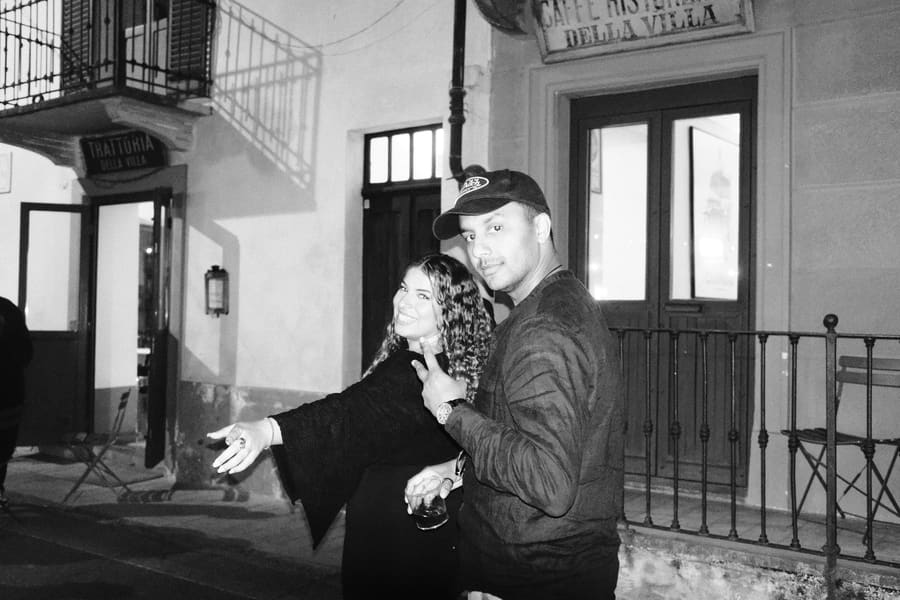 Two teammates pointing and smiling outside a trattoria at night