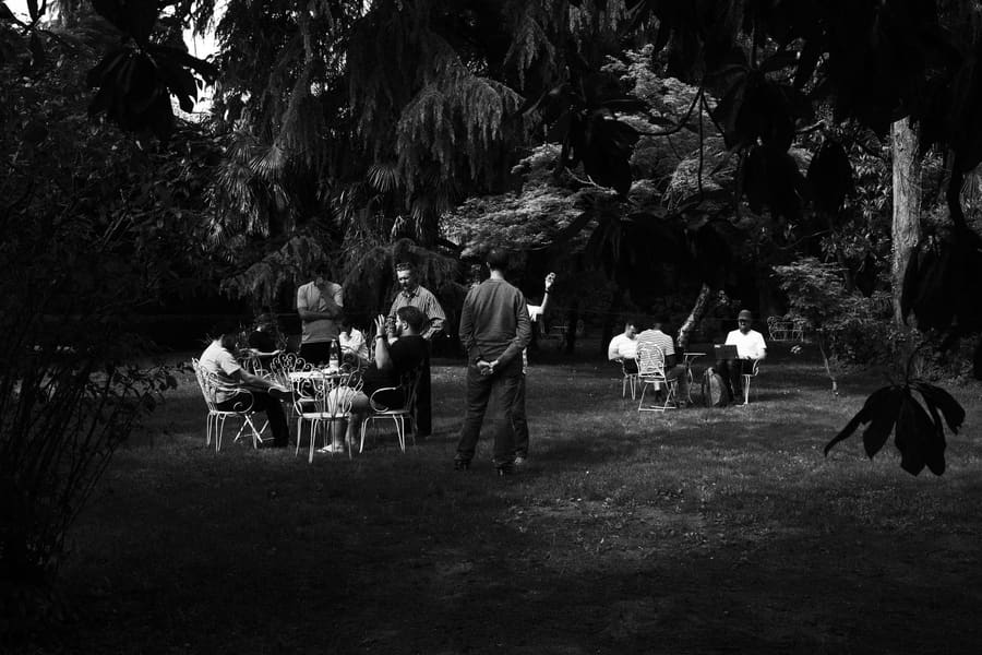 Teammates gathered at garden tables in the shade, some working on laptops