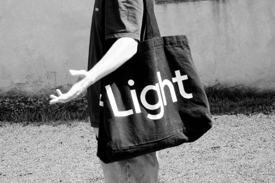 A close-up of someone carrying a black Light tote bag over their shoulder